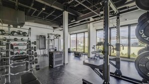 Ein Fitnessstudio mit Gewichte, einer Bank und einem großen Fenster mit Blick ins Freie.