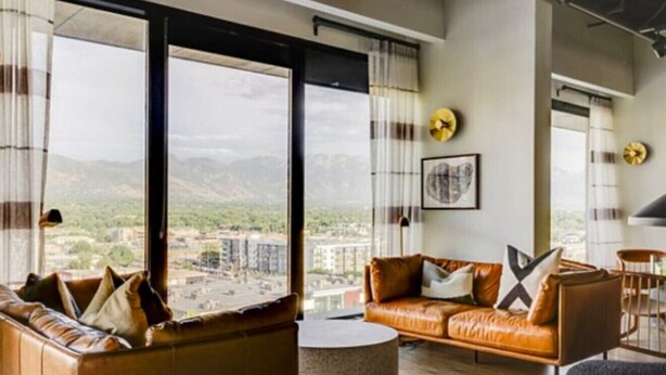 Ein modernes Wohnzimmer mit Ledersofas, einem runden Couchtisch und großen Fenstern mit Blick auf die Stadt.