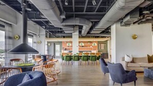 Una oficina amplia de concepto abierto con una cocina moderna, techos altos con conductos a la vista y vistas a la ciudad.
