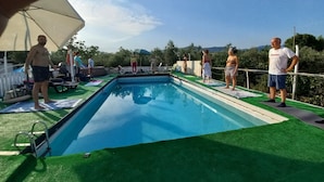 A swimming pool with a green deck, surrounded by lounge chairs and umbrellas. - AL RIFUGIO (Montecorvino Pugliano)