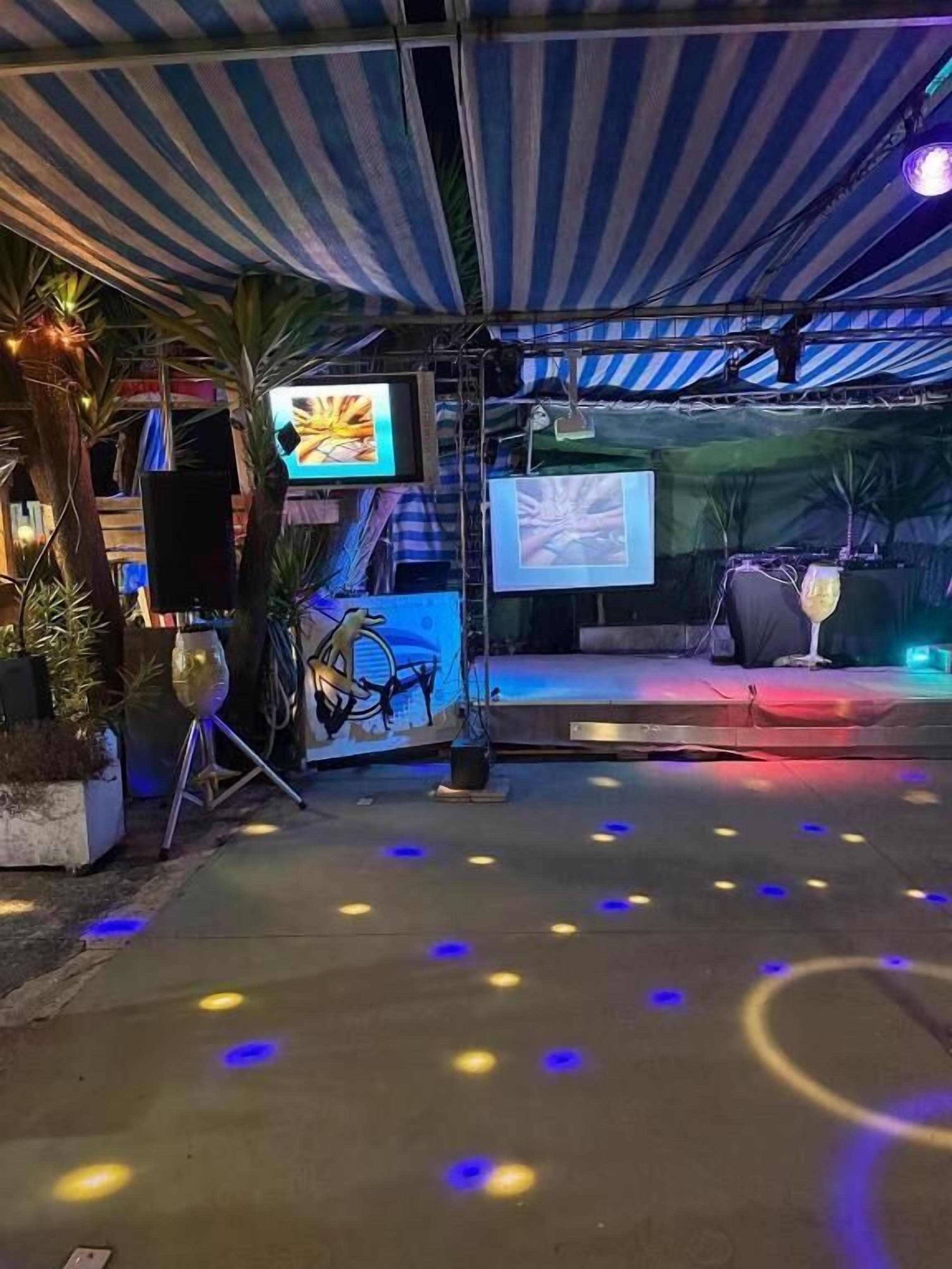 Un espacio para eventos al aire libre con escenario, pantallas de proyección e iluminación ambiental.