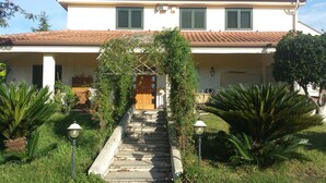 A two-story house with a tiled roof, a wooden door, and a staircase leading to the entrance. - AL RIFUGIO (Montecorvino Pugliano)