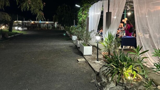 An outdoor event area with a covered seating area, potted plants, and a pathway leading to a building. - AL RIFUGIO (Montecorvino Pugliano)