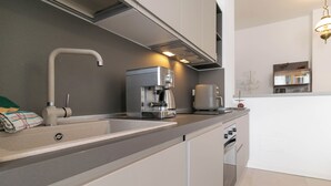 Una cocina moderna con horno integrado, cafetera y lavamanos.