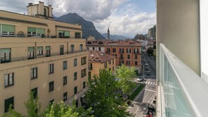 Vista desde un balcón con vista a un paisaje urbano que incluye edificios, una calle y montañas al fondo.