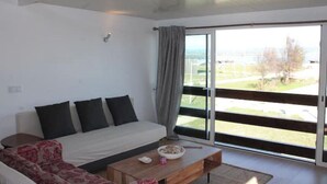 Een moderne woonkamer met een bank, een bijzettafeltje en uitzicht door grote glazen deuren.