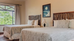 A hotel room with two beds, a window with curtains, a night sky painting, and a lamp.
