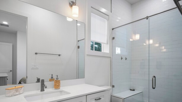 A modern bathroom with a white sink, a large mirror, and a glass shower enclosure. - Angle of the Sun 301 SOU (Port Aransas)