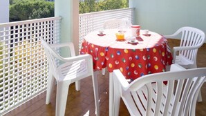 A balcony with a table and chairs, a white fence, and a view of buildings and trees. - Residence Athena-two room apartment 26 B4*++ for 4 persons (Bibione)