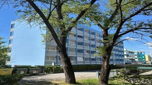 Un edificio moderno con fachada de vidrio, rodeado de árboles y un sendero.