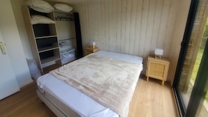 A bedroom with a bed, wooden wardrobe, and a window. - Chalet Lesconil (Plobannalec-Lesconil)