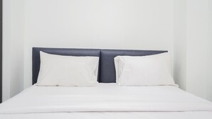 A bed with a dark headboard and white bedding.