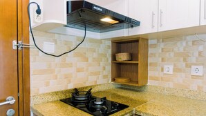 A kitchen with a gas stove, a built-in oven, a range hood, and a wooden shelf. - Spacious and Homey 2BR at Signature Park Grande Apartment (Jakarta)