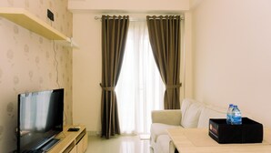 A living room with a flat-screen TV, a sofa, a coffee table, and a water bottle on a tray. - Spacious and Homey 2BR at Signature Park Grande Apartment (Jakarta)