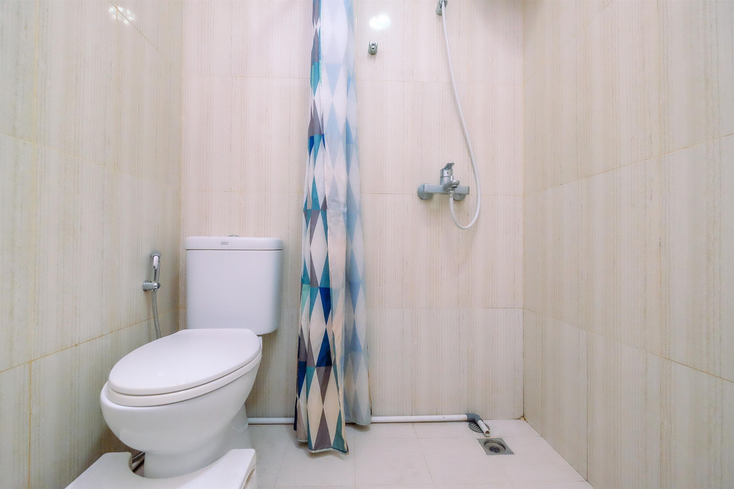 Une salle de bain avec des toilettes, une douche et des murs carrelés.