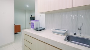 A modern kitchen with white cabinets, a stainless steel sink, and a countertop with a coffee machine and storage containers.