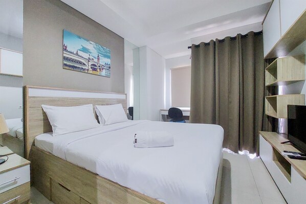Une chambre d’hôtel avec un grand lit, un bureau, une chaise, une télévision et un tableau au mur.