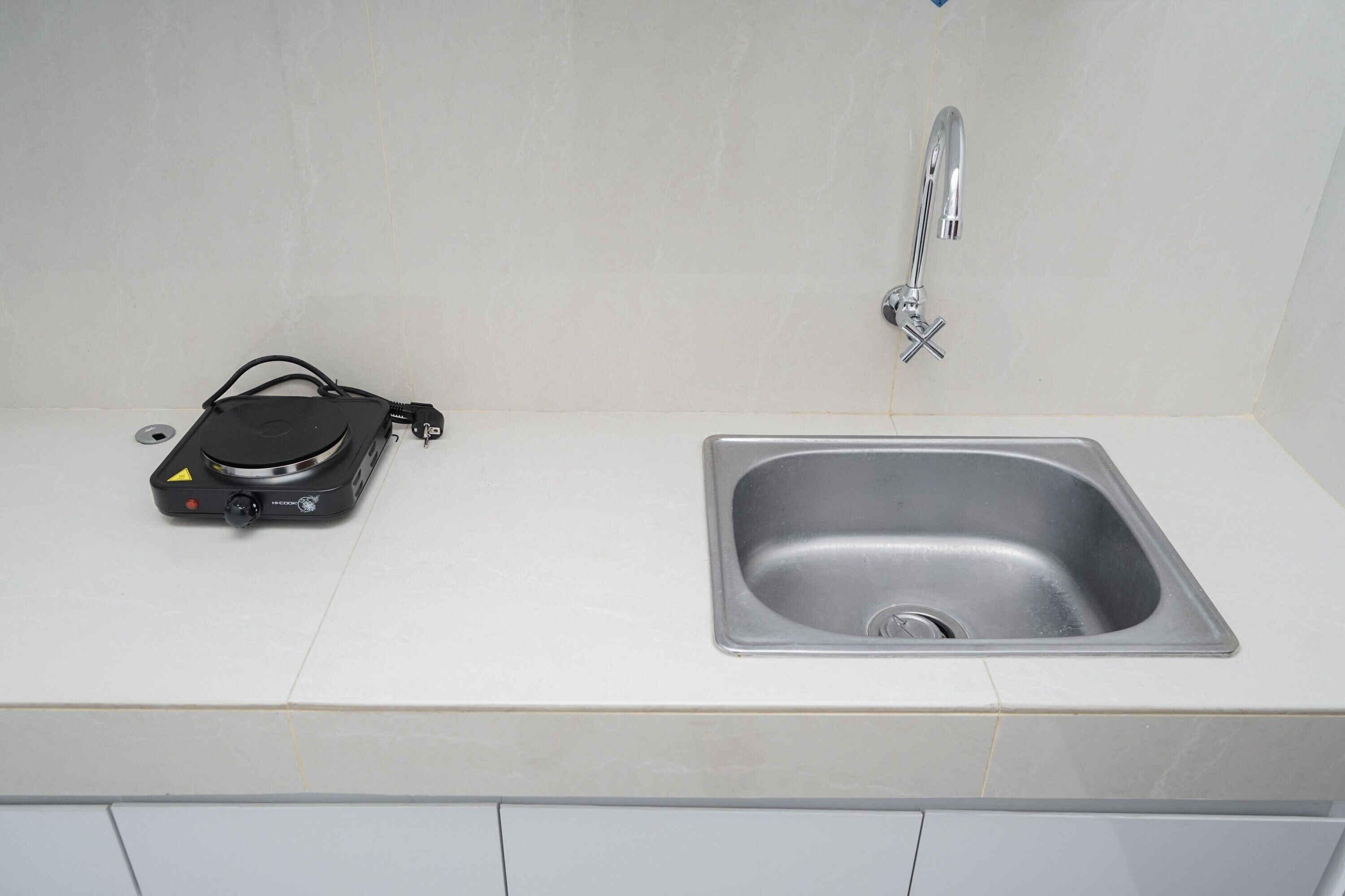 A kitchen with a stainless steel sink and a black portable heater on the countertop.