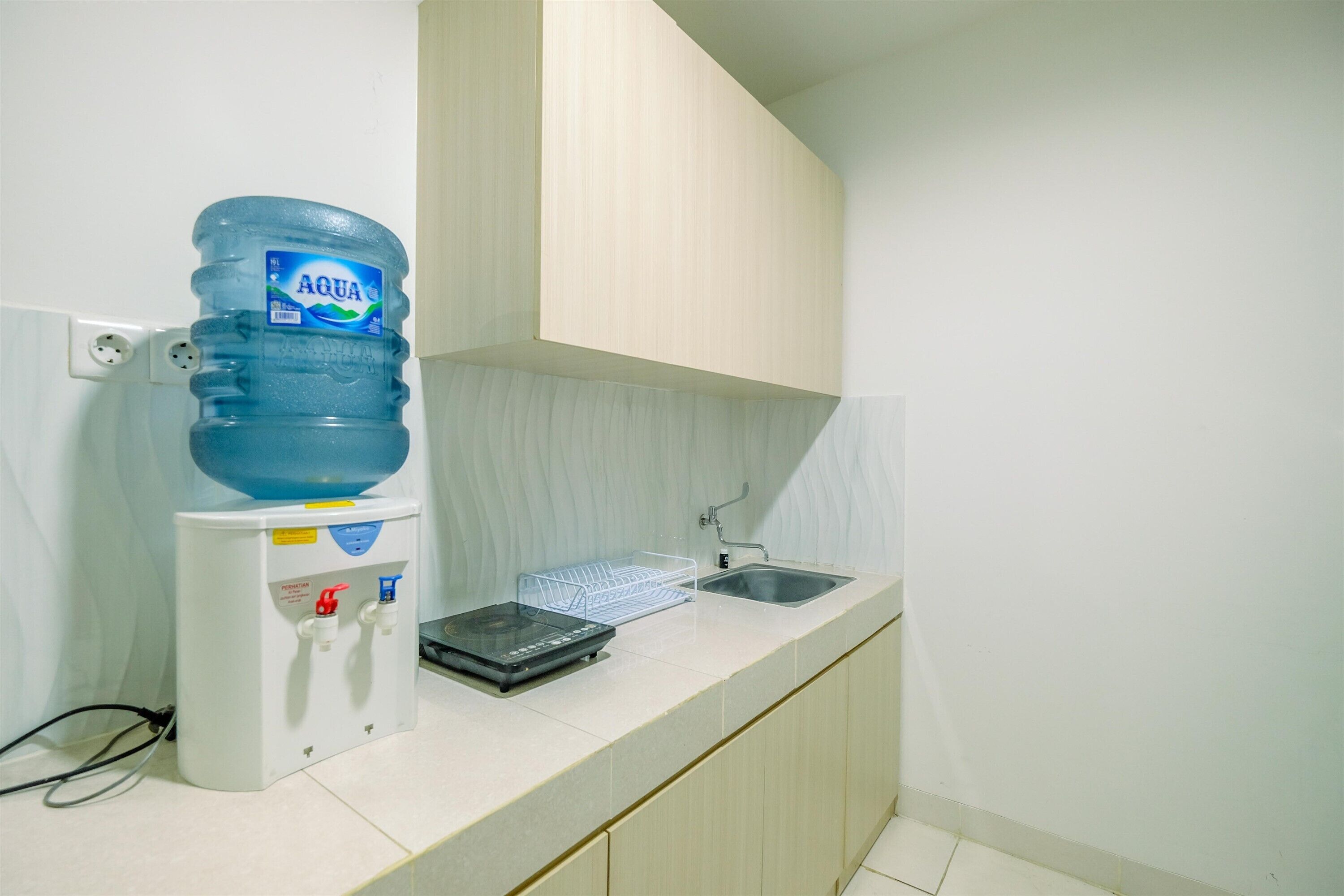 Una kitchenette con dispensador de agua, una balanza y un lavabo.