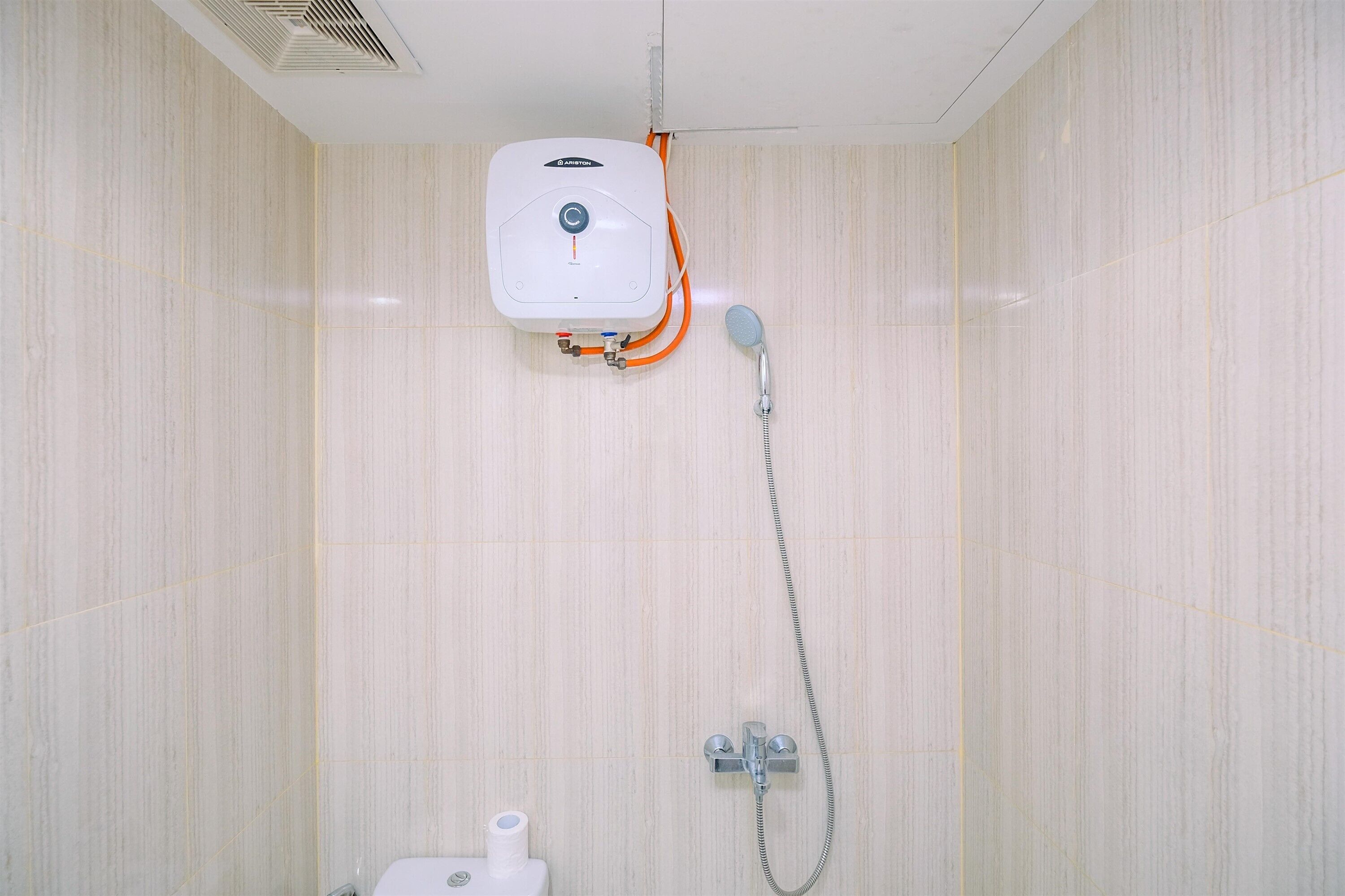 Une salle de bain équipée d’un chauffe-eau, d’une douche et de toilettes.
