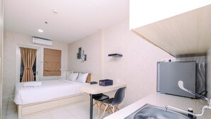 Hotellihuone, jossa on sänky, työpöytä, tuoli, pesuallas ja jääkaappi.