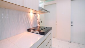 A modern kitchen with a built-in stove, a range hood, and a white tiled backsplash. - Spacious 2BR at Sentul Tower Apartment (Citaringgul)