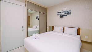 Ein Hotelzimmer mit einem großen Bett, einem Kleiderschrank, einem Spiegel und Bildern an der Wand.