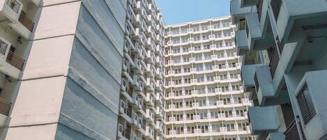 A high-rise residential building with multiple balconies and air conditioning units.