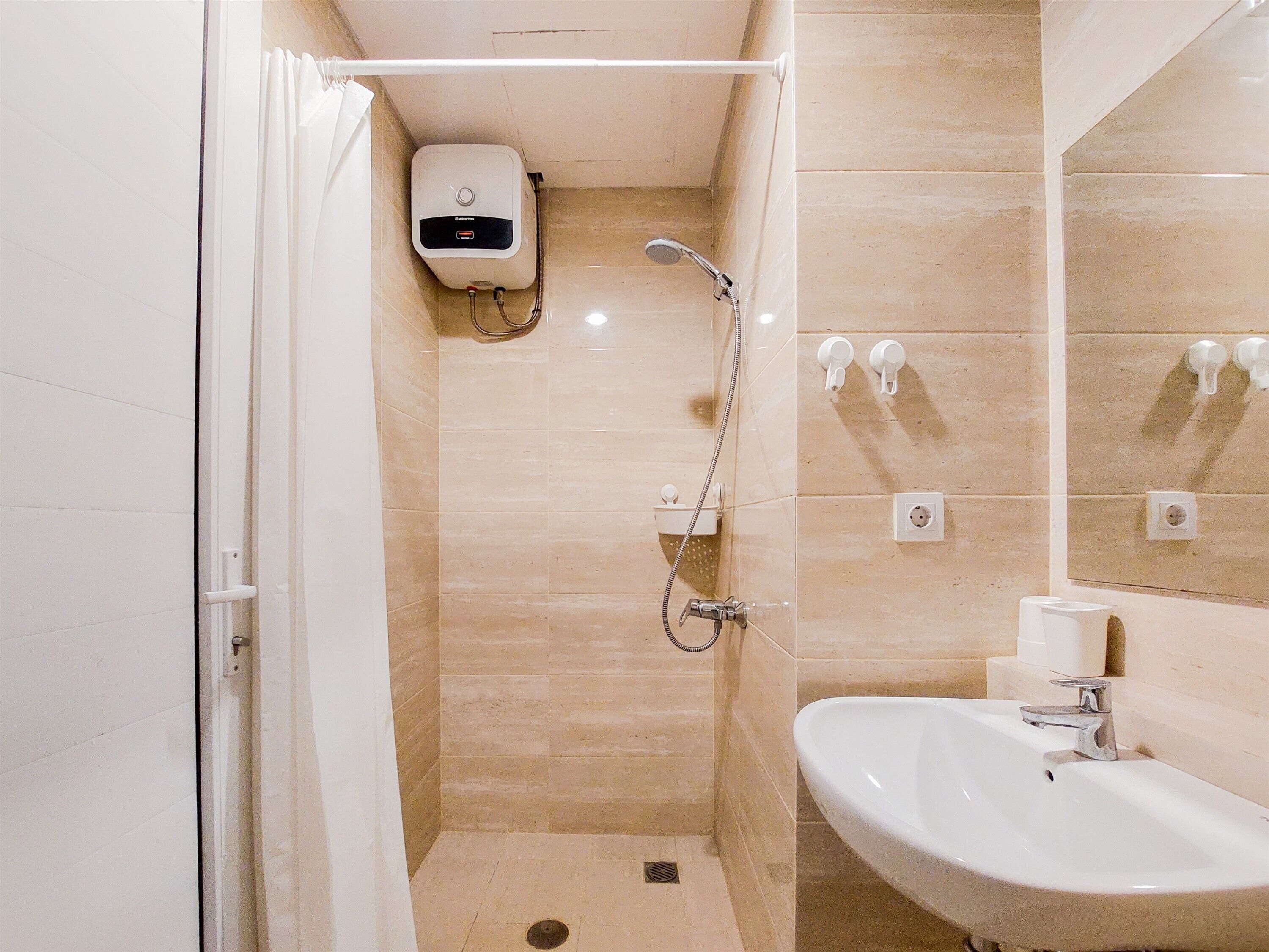 A modern bathroom with a shower, a sink, and a hand dryer.