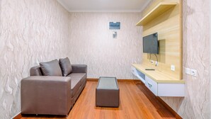 A modern living room with a sofa, ottoman, and built-in TV shelf. - Comfortable and Modern 2BR Sentul Tower Apartment (Citaringgul)