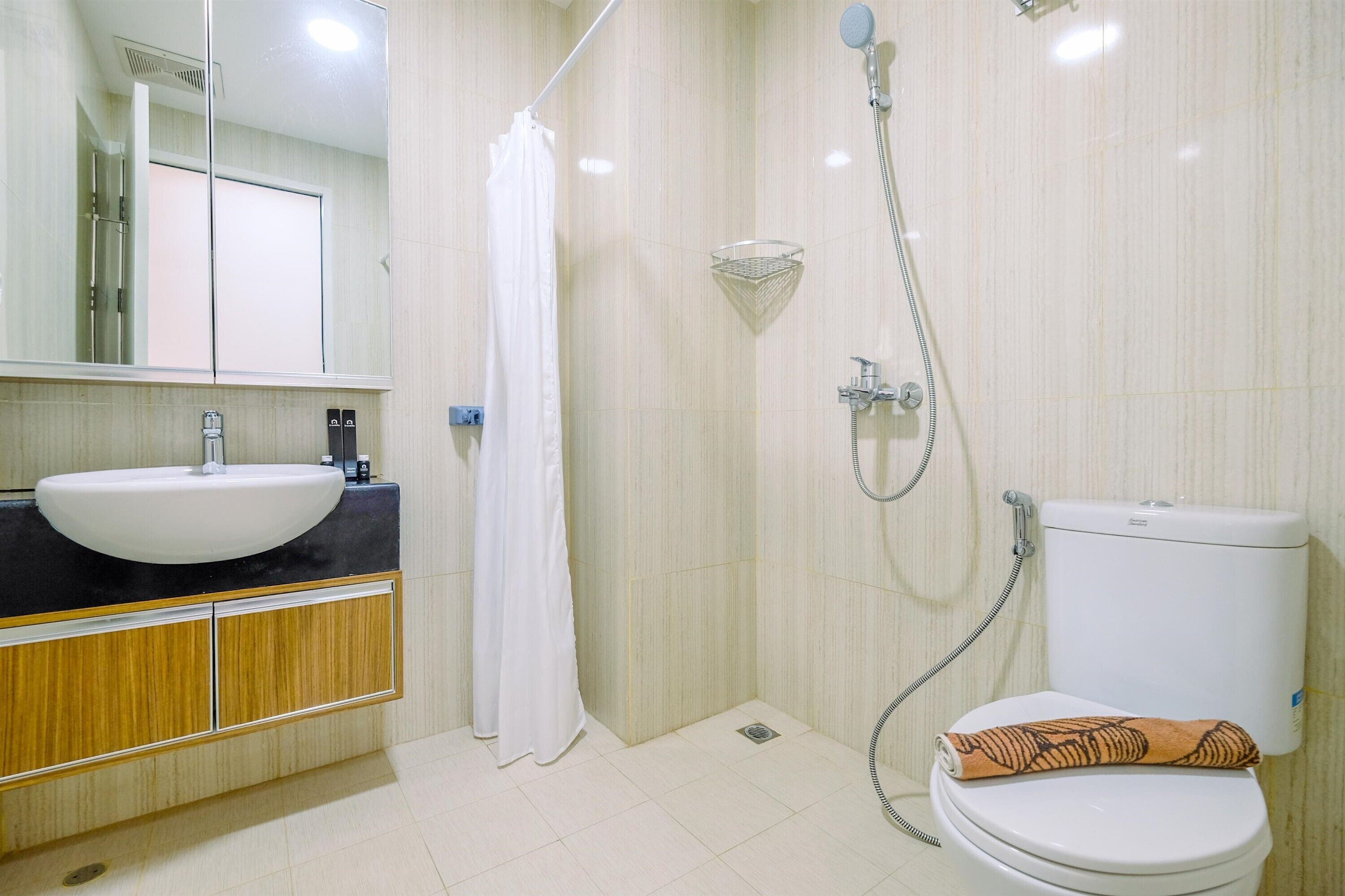 A bathroom with a sink, toilet, shower, and mirror.