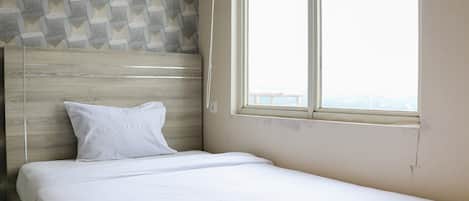 A neatly made bed with a wooden headboard and a window with a view.