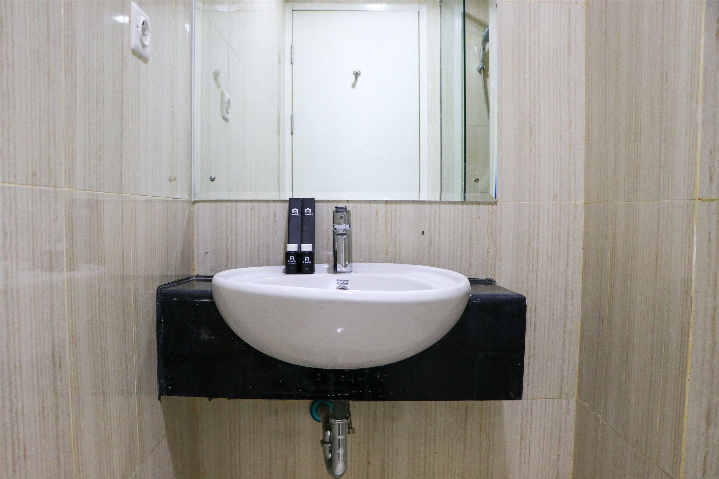 A bathroom with a white sink, black countertop, and a mirror above it.
