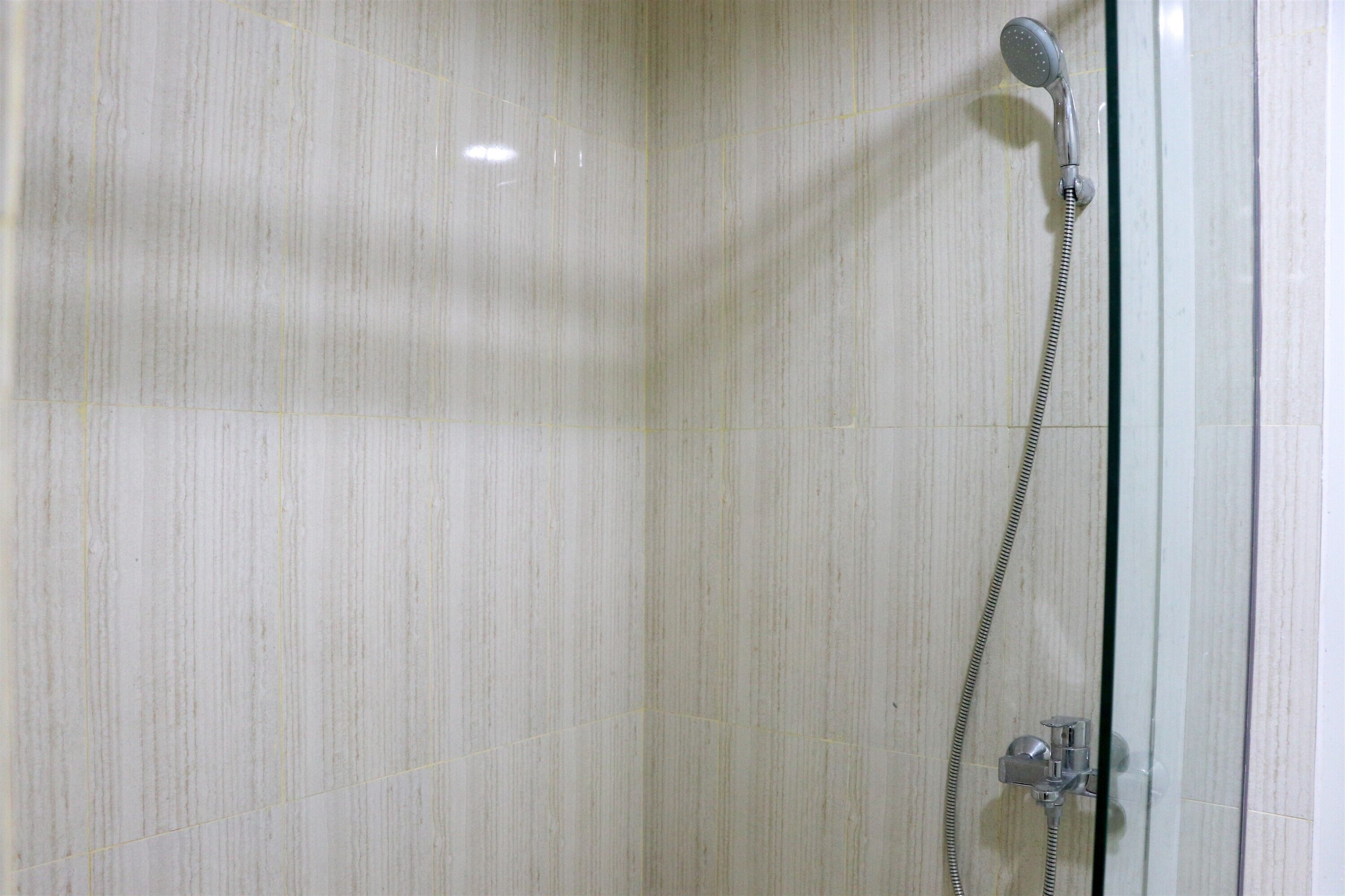 A shower with a handheld showerhead and a wall-mounted control valve.