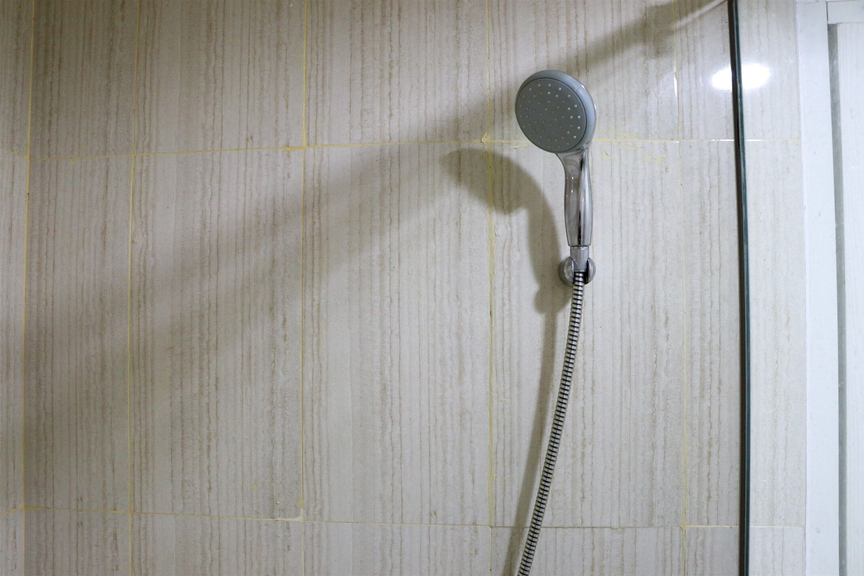 Un pommeau de douche fixé à un mur carrelé.
