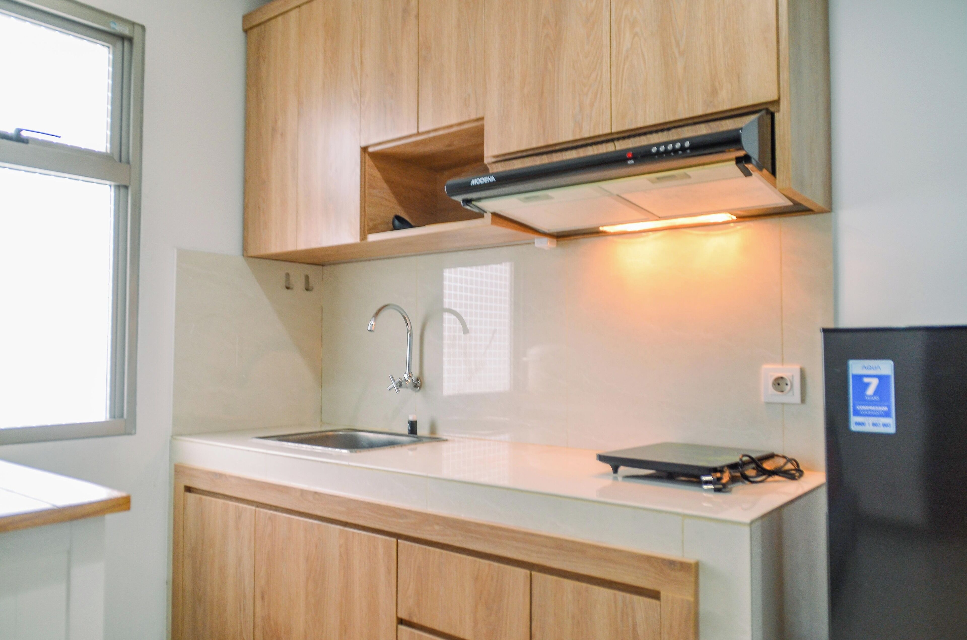 A kitchen with wooden cabinets, a stainless steel sink, and a black refrigerator.