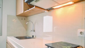 A kitchen with a stainless steel sink, a wooden countertop, and a black induction cooktop. - Chic and Cozy 2BR Apartment at Springwood Residence (Tangerang)