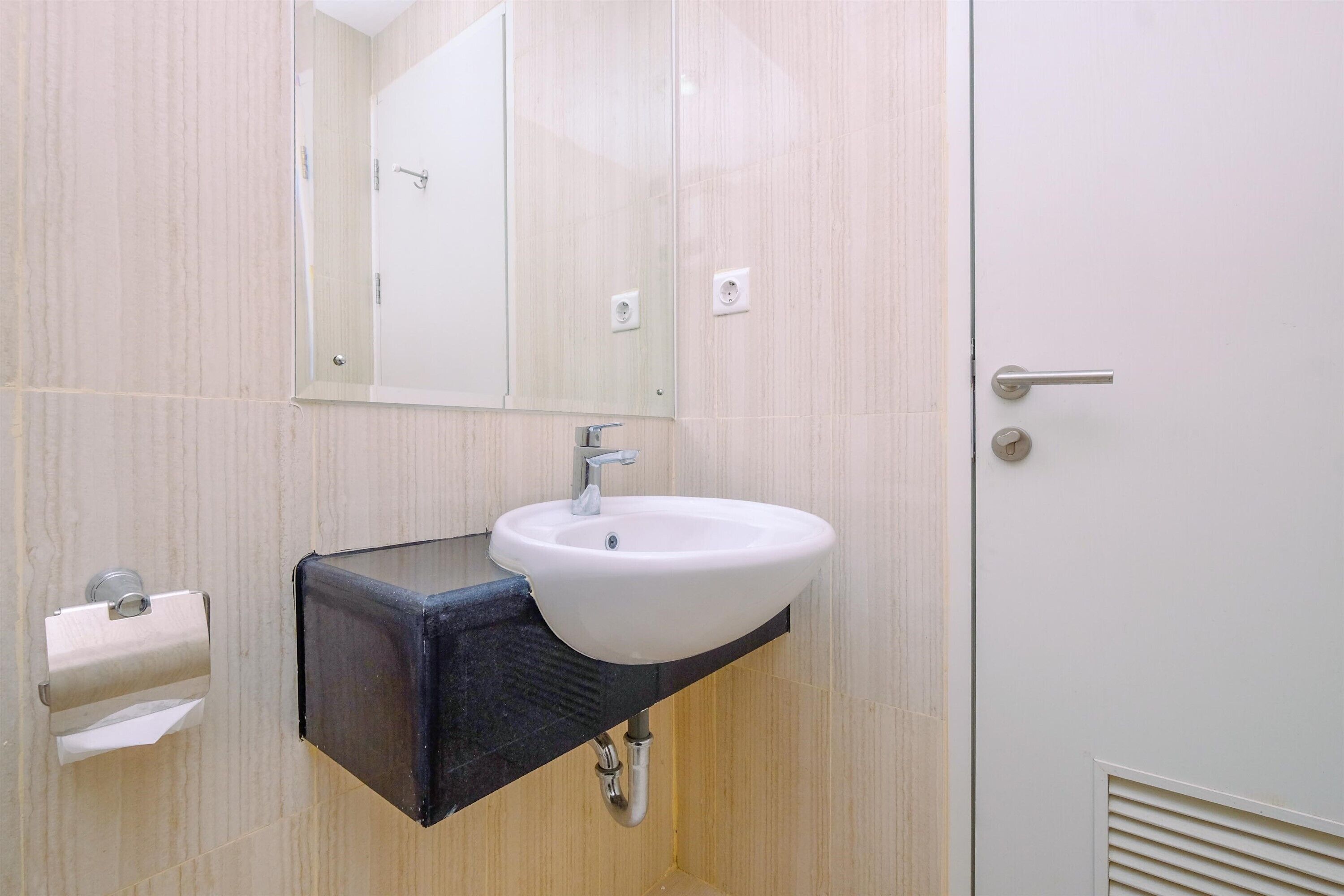 Un baño con un lavabo blanco, un espejo y un dispensador de toallas.