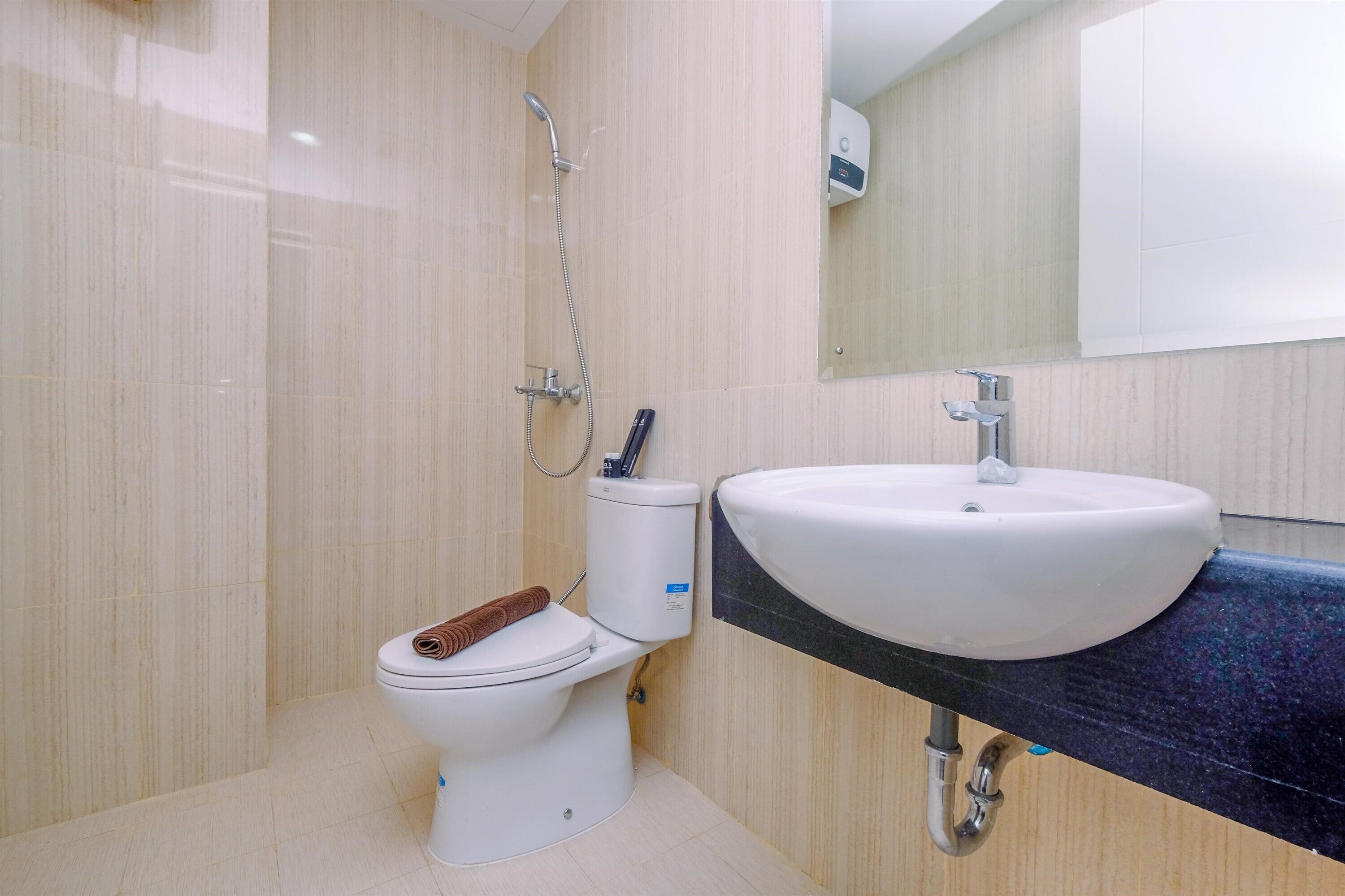 Une salle de bain moderne avec des toilettes blanches, une douche et un lavabo.