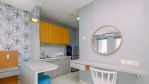 A modern kitchen with a white countertop, a built-in oven, and a wooden cabinet. - Cozy Studio at Sentul Tower Apartment (Citaringgul)