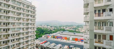 A high-rise building with multiple balconies and a parking area below.