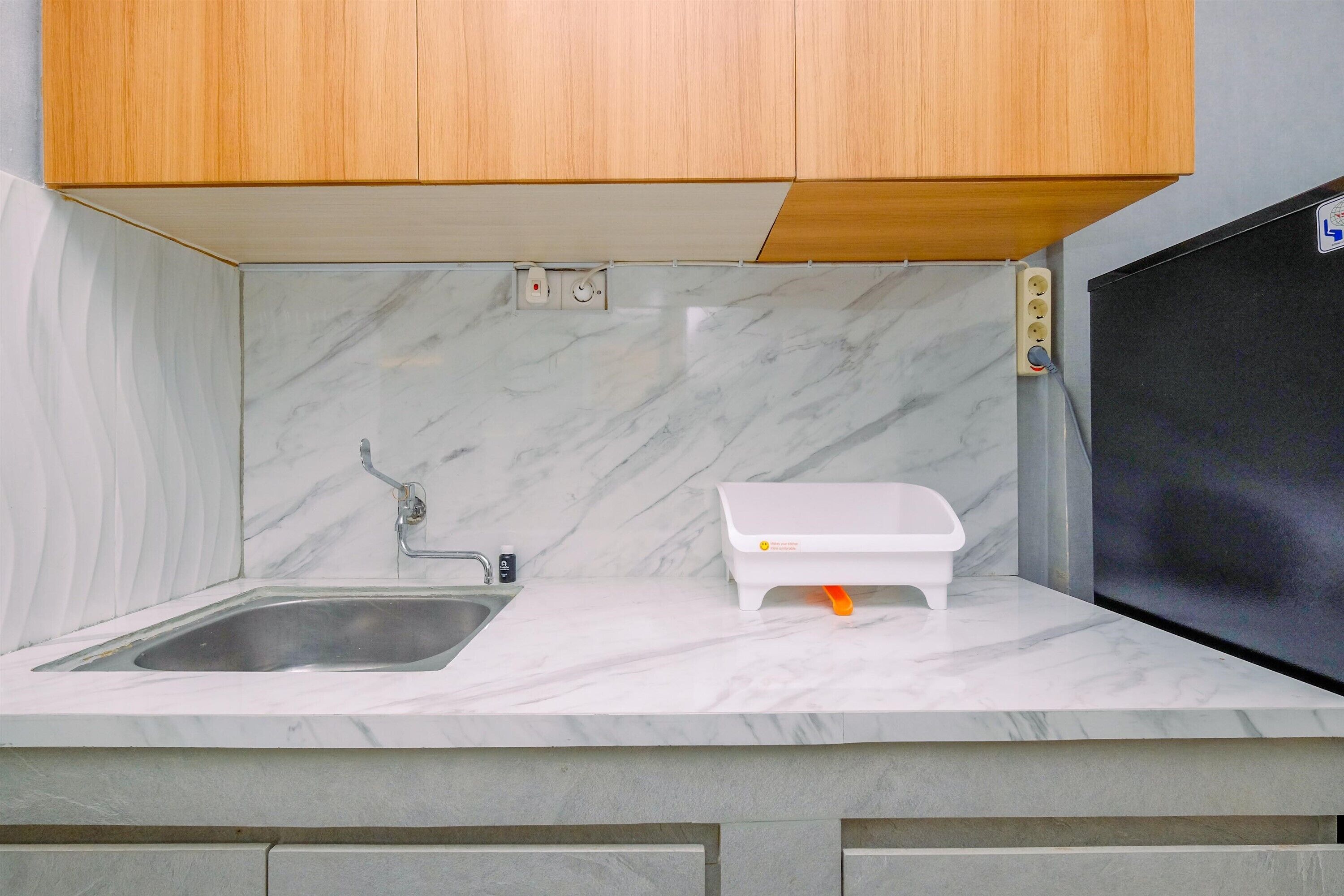 A kitchen with a marble countertop, a sink, and wooden cabinets.