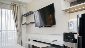 Een hotelkamer met een bed, een flatscreen televisie aan de muur, een minibar en een waterdispenser.