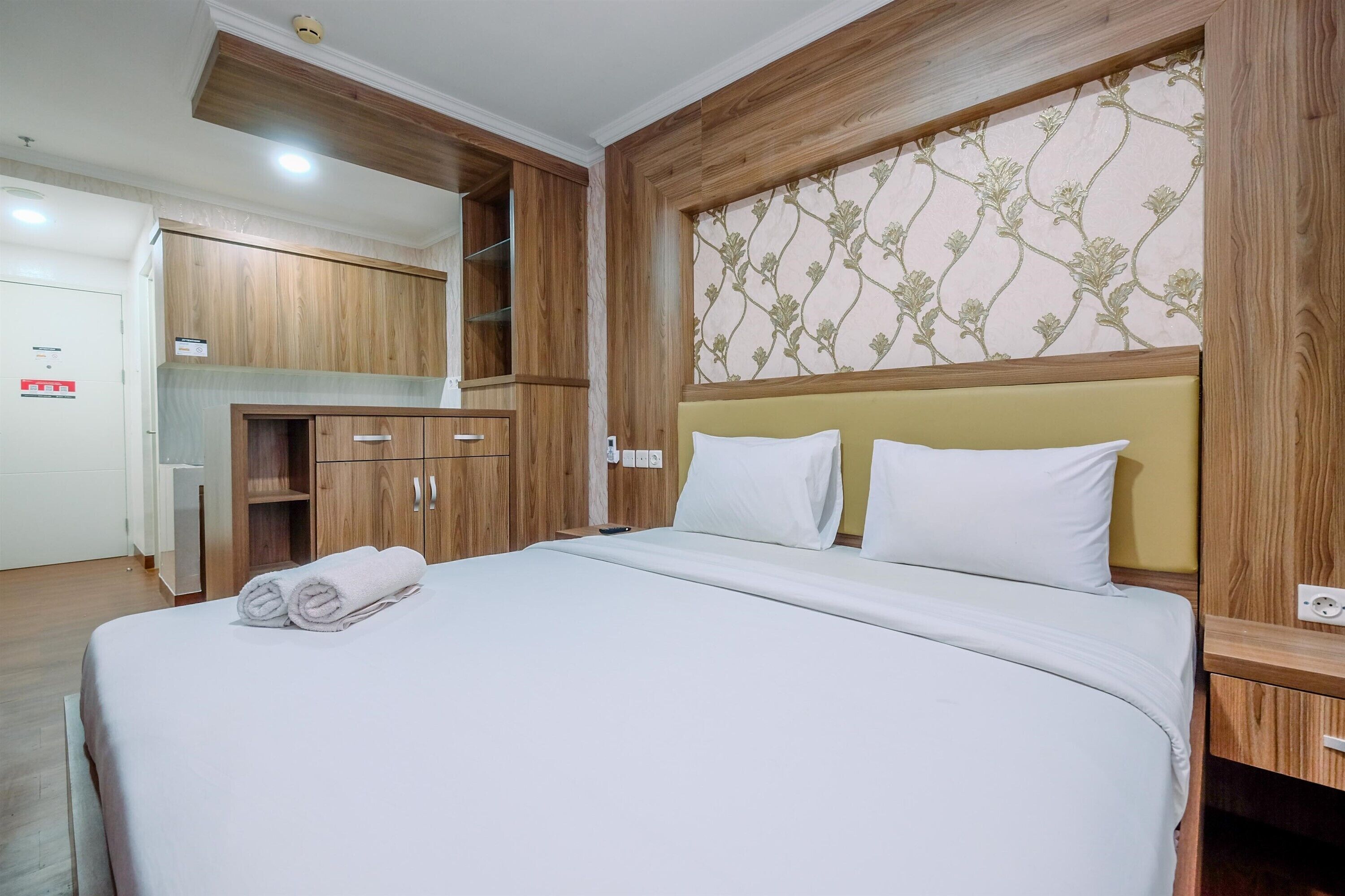 Habitación de hotel con una cama grande, armario de madera y una pequeña kitchenette.