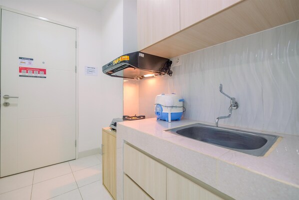 A kitchen with a sink, a water dispenser, and a cabinet. - Cozy Living 2BR Sentul Tower Apartment (Citaringgul)