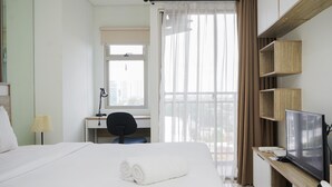 Une chambre d’hôtel équipée d’un lit, d’un bureau, d’une chaise, d’une télévision et d’une fenêtre avec des rideaux.