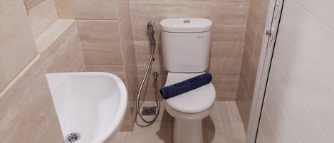 Et badeværelse med bidét, toilet og brusebad.