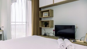 Een hotelkamer met een bed, een televisie, een bureau en een raam met gordijnen.
