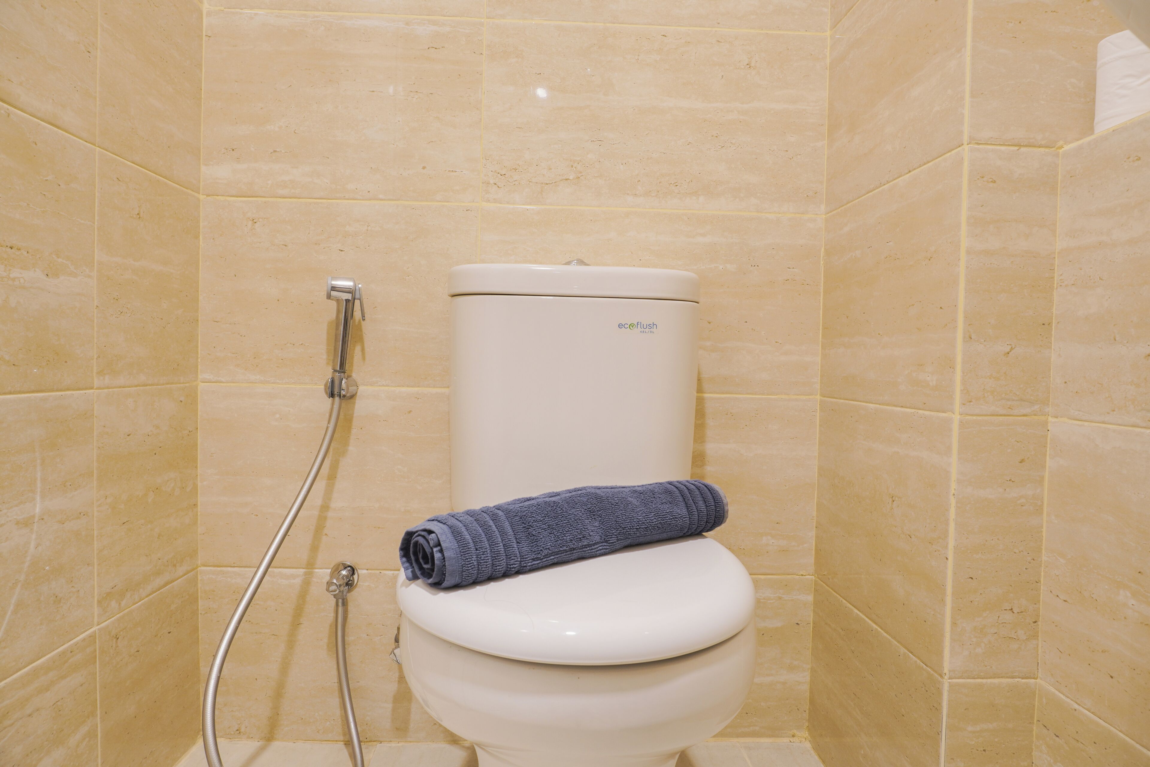 A bathroom with a toilet, a shower, and beige tiled walls.