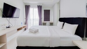 A hotel room with a bed, a TV, a desk, and a window with curtains. - Serene Studio at Springwood Residence Tangerang Apartment (Tangerang)